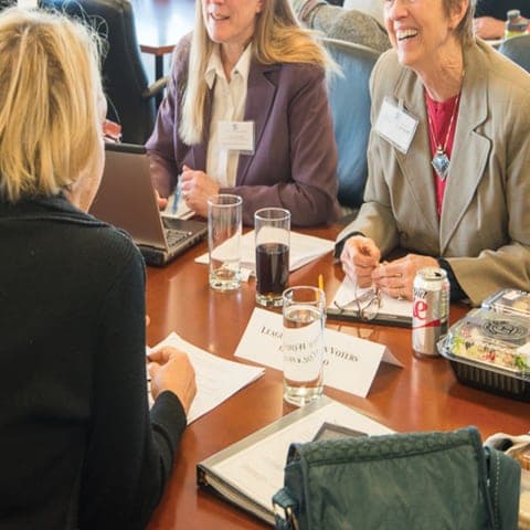 Attorneys and community advocates with name badges talking around a conference table