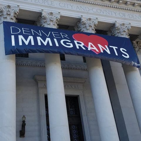 A Denver Loves Immigrants banner hung between the columns of the Denver City and County Building