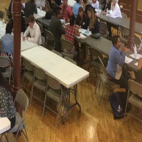 Volunteers and clients going over paperwork at folding tables in a clinic hall